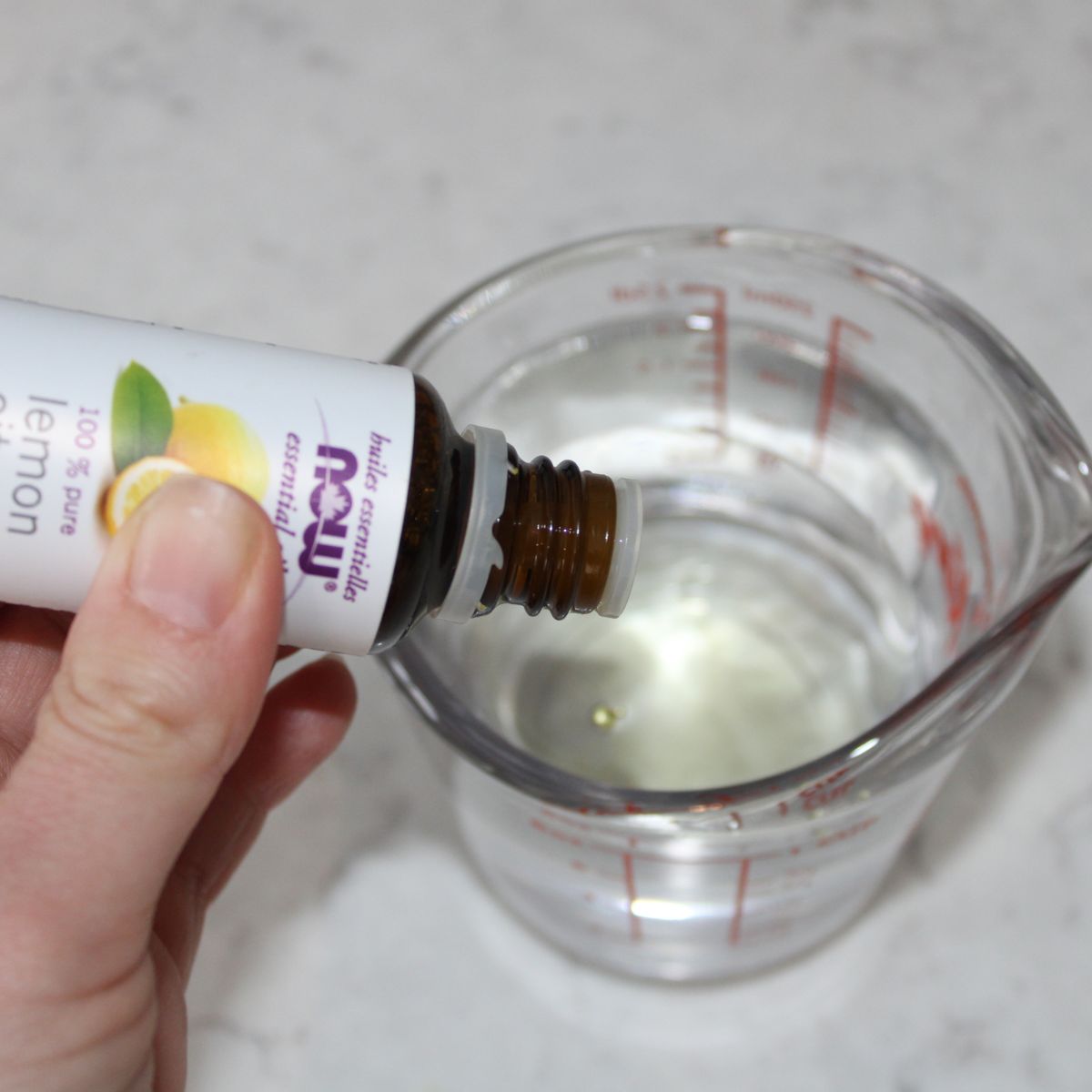 lemon essential oil drops added into vinegar in a measuring cup