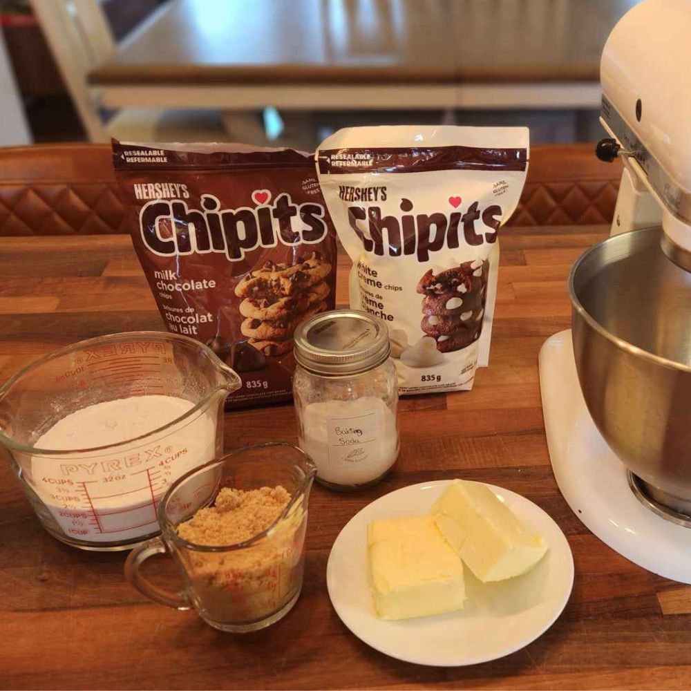 ingredients for chocolate chip cookies next to a stand mixer on a wood counter