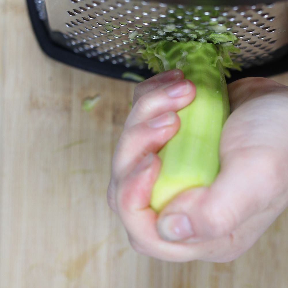 hand grating zucchini on a box grater