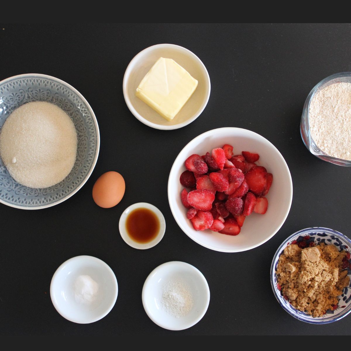 baking ingredients in individual bowls on a black countertop