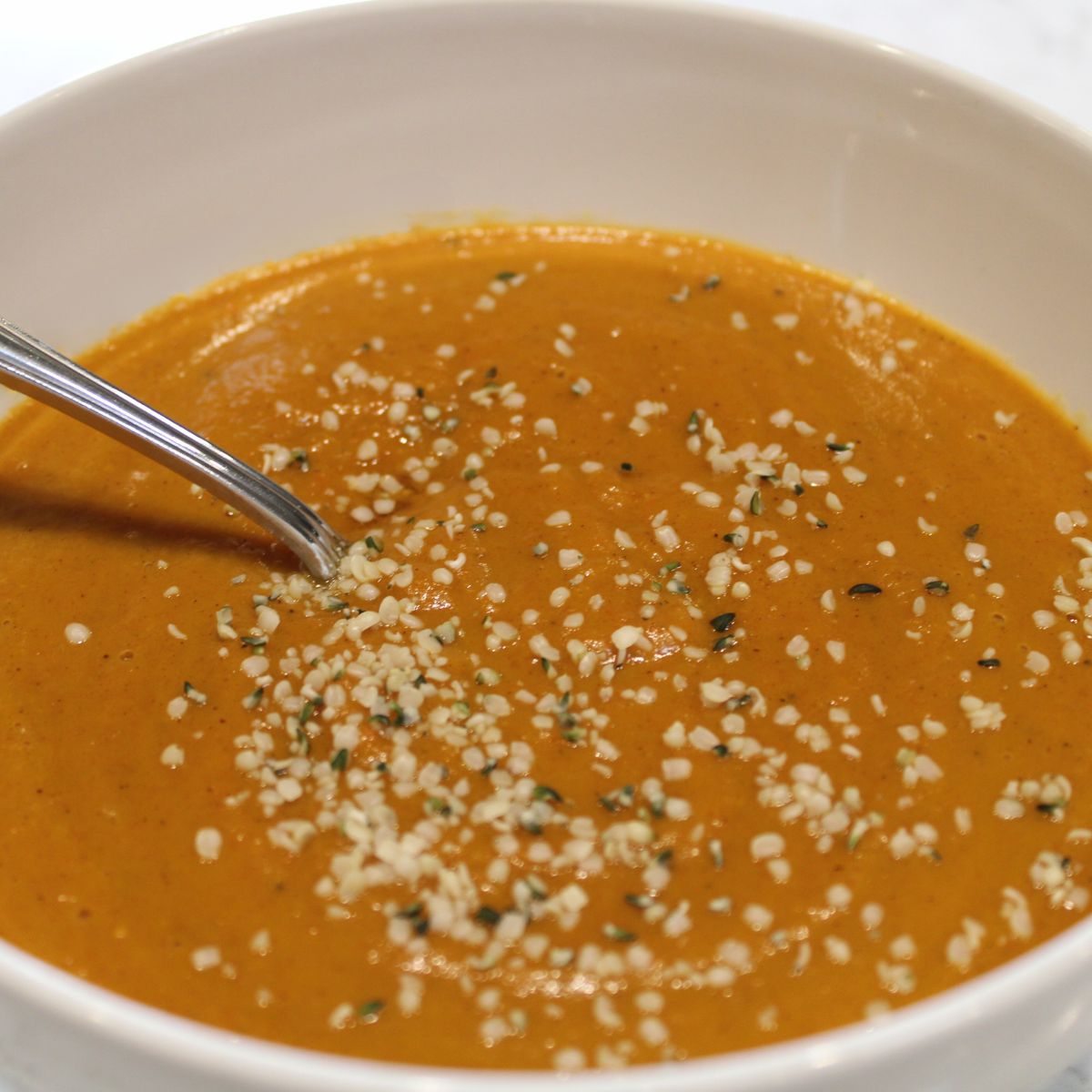 bowl of carrot soup garnished with hemp seeds