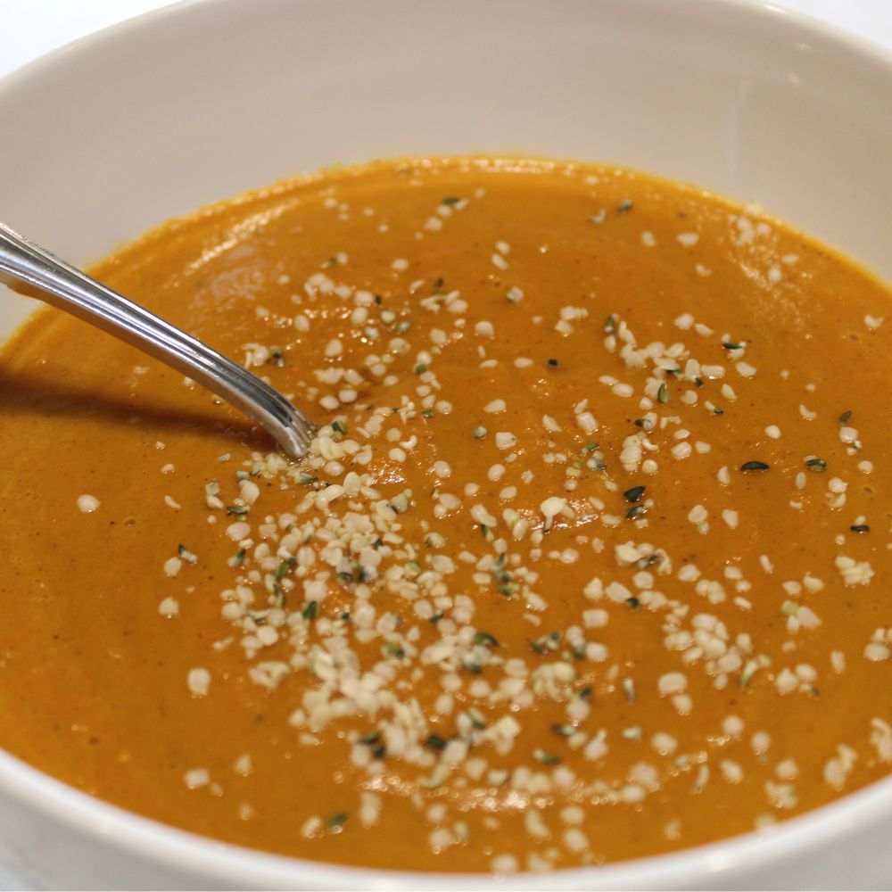 carrot soup in a bowl, garnished with hemp seeds