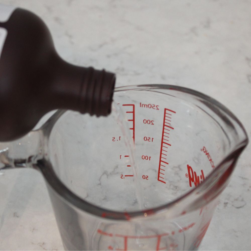 hydrogen peroxide being poured into a measuring cup