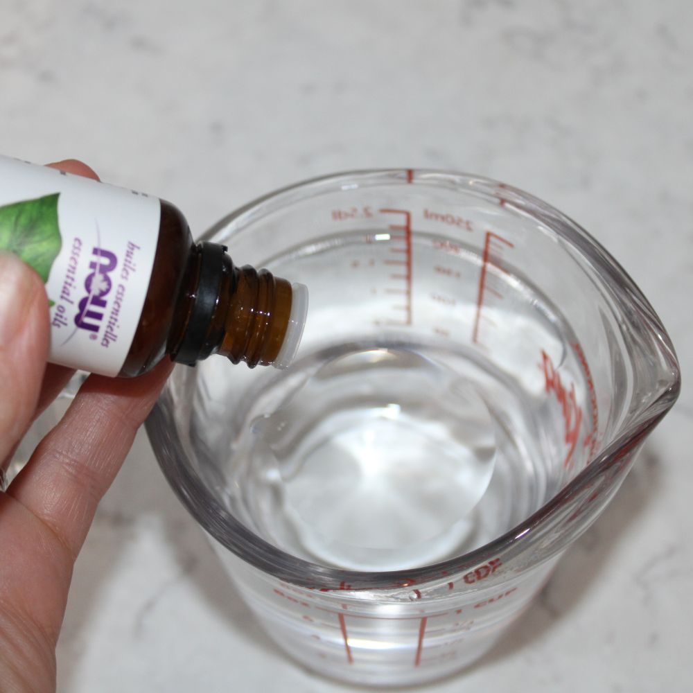 essential oil drops going into liquid in a measuring cup