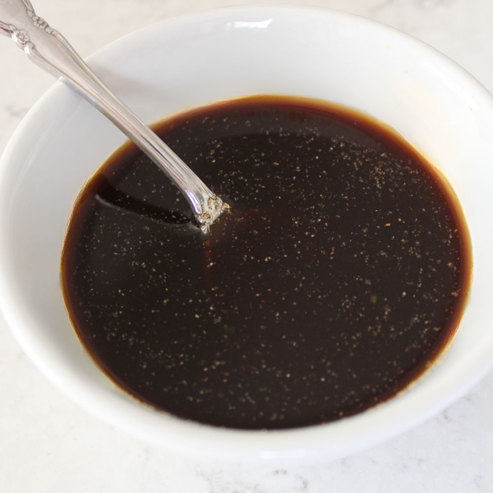 close up of stir fry sauce with a spoon in the bowl