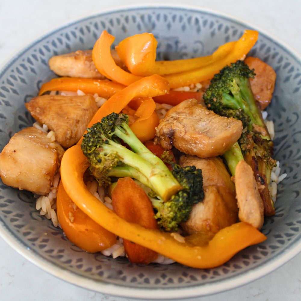 close up of chicken stir fry with orange bell peppers and broccoli