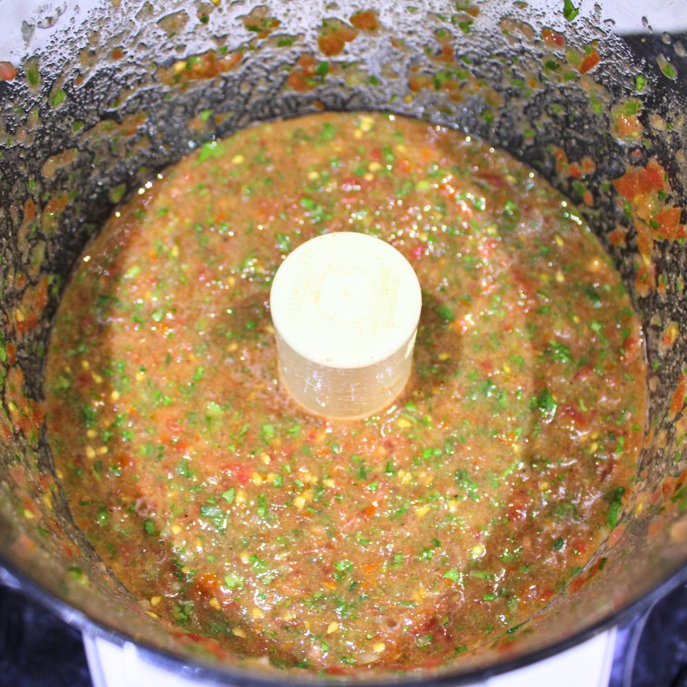 Blended restaurant style salsa in a food processor, featuring a vibrant mix of tomatoes, cilantro, and green onions.