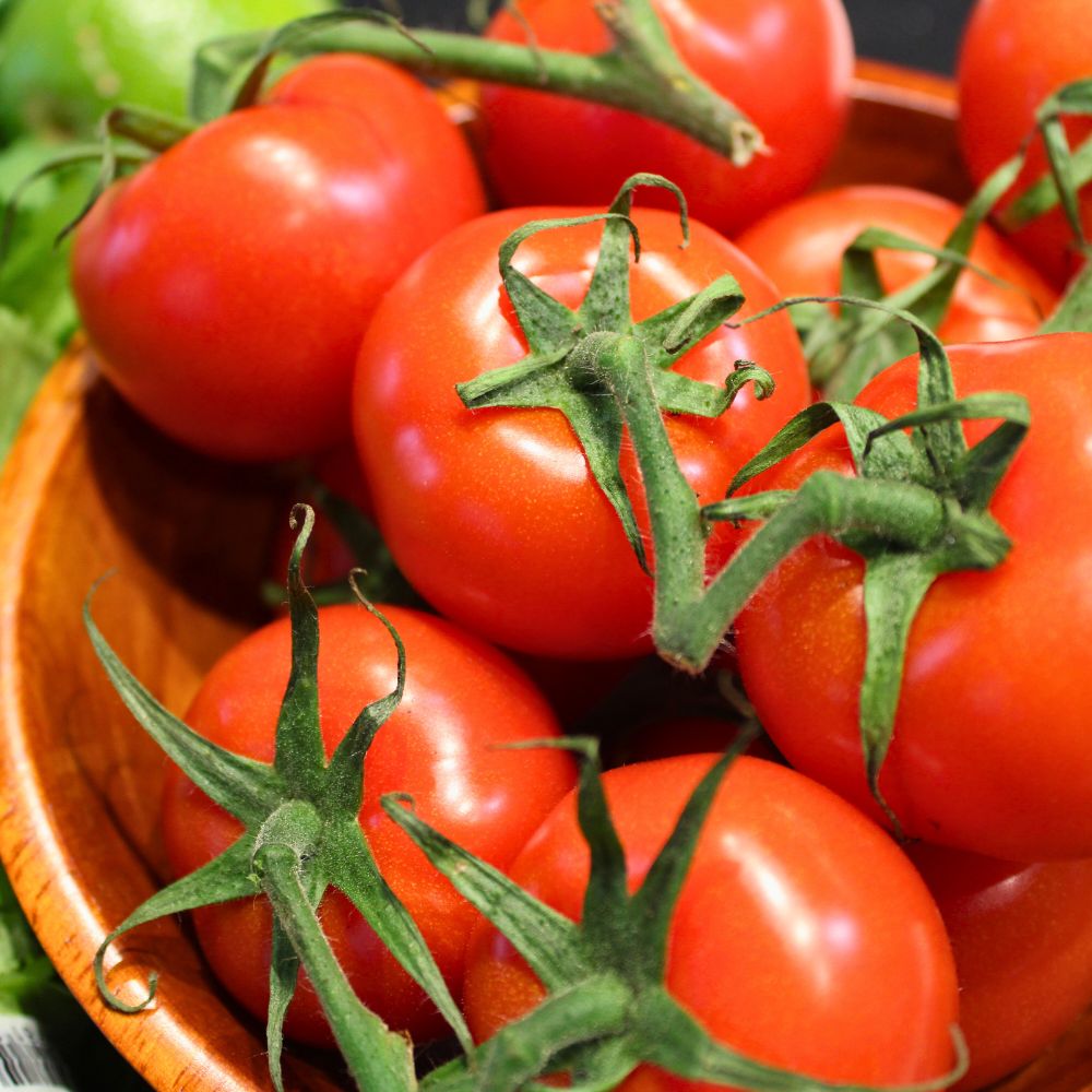 close up of tomatoes on the vine in a wooden bowl