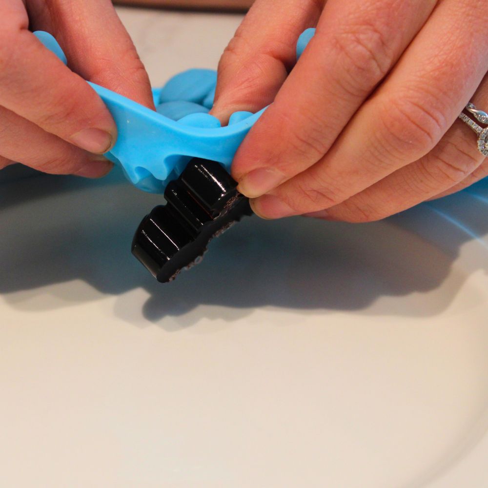 hands popping homemade gummies out of silicone mold and onto a plate 