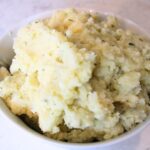 close up of fluffy mashed potatoes piled high in a bowl