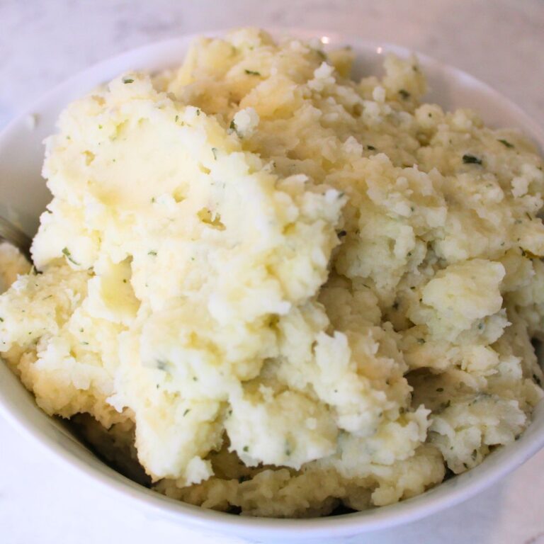 close up of fluffy mashed potatoes piled high in a bowl