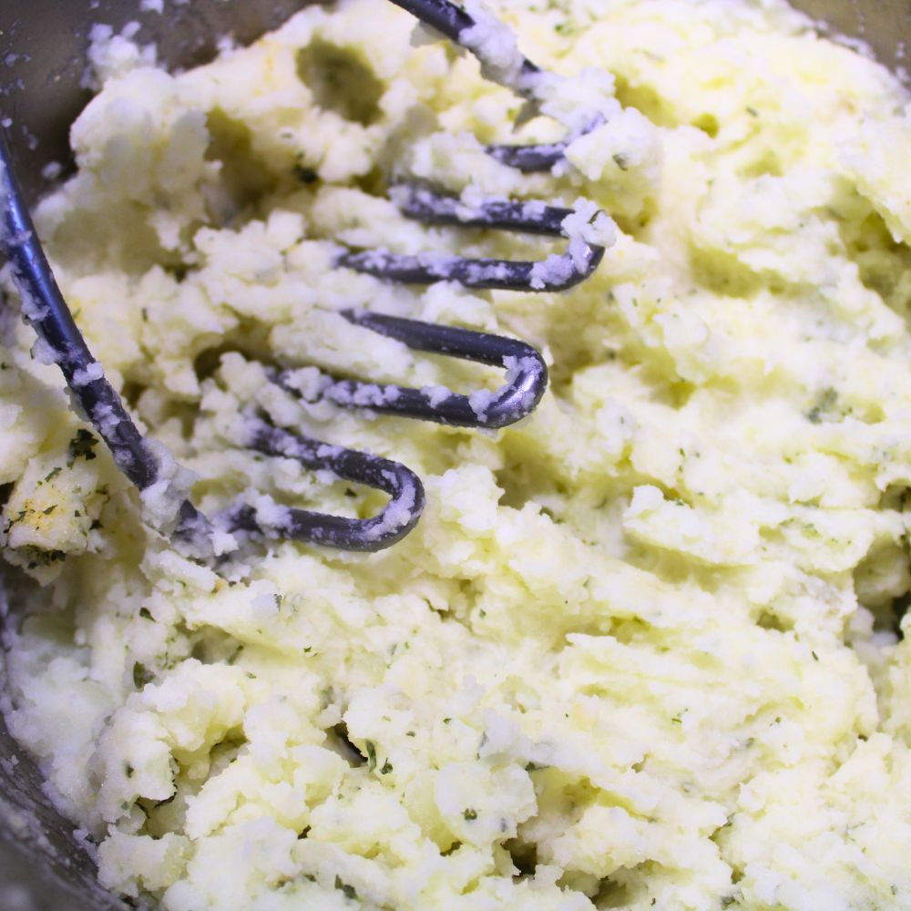 mashed potatoes and a potato masher in a pot