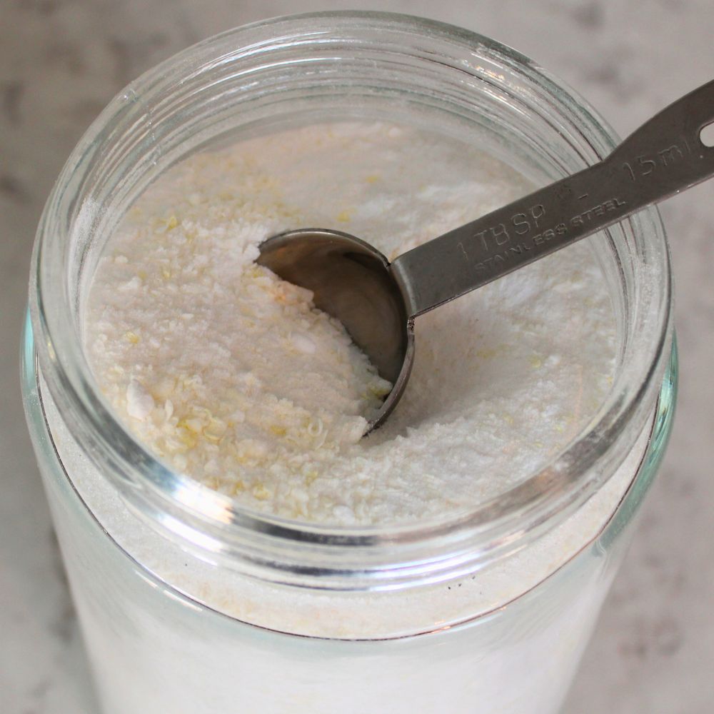 Overhead view of a glass jar filled with homemade powder laundry detergent with a metal tablespoon